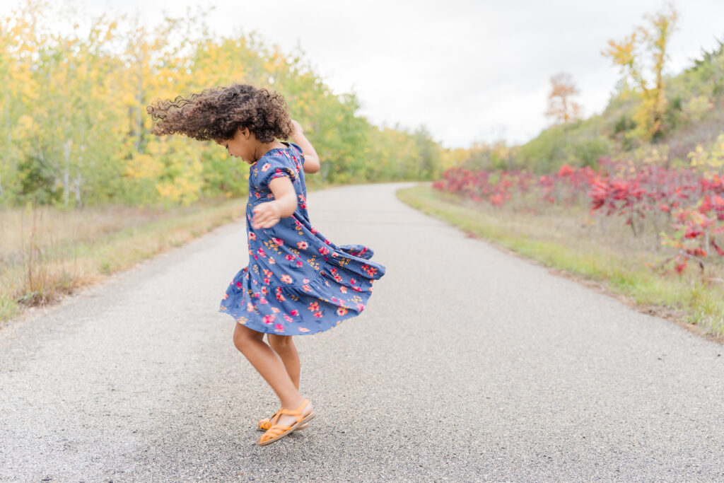 Little girl twirling on a paved trail at Delagoon Park in Fergus Falls MN 