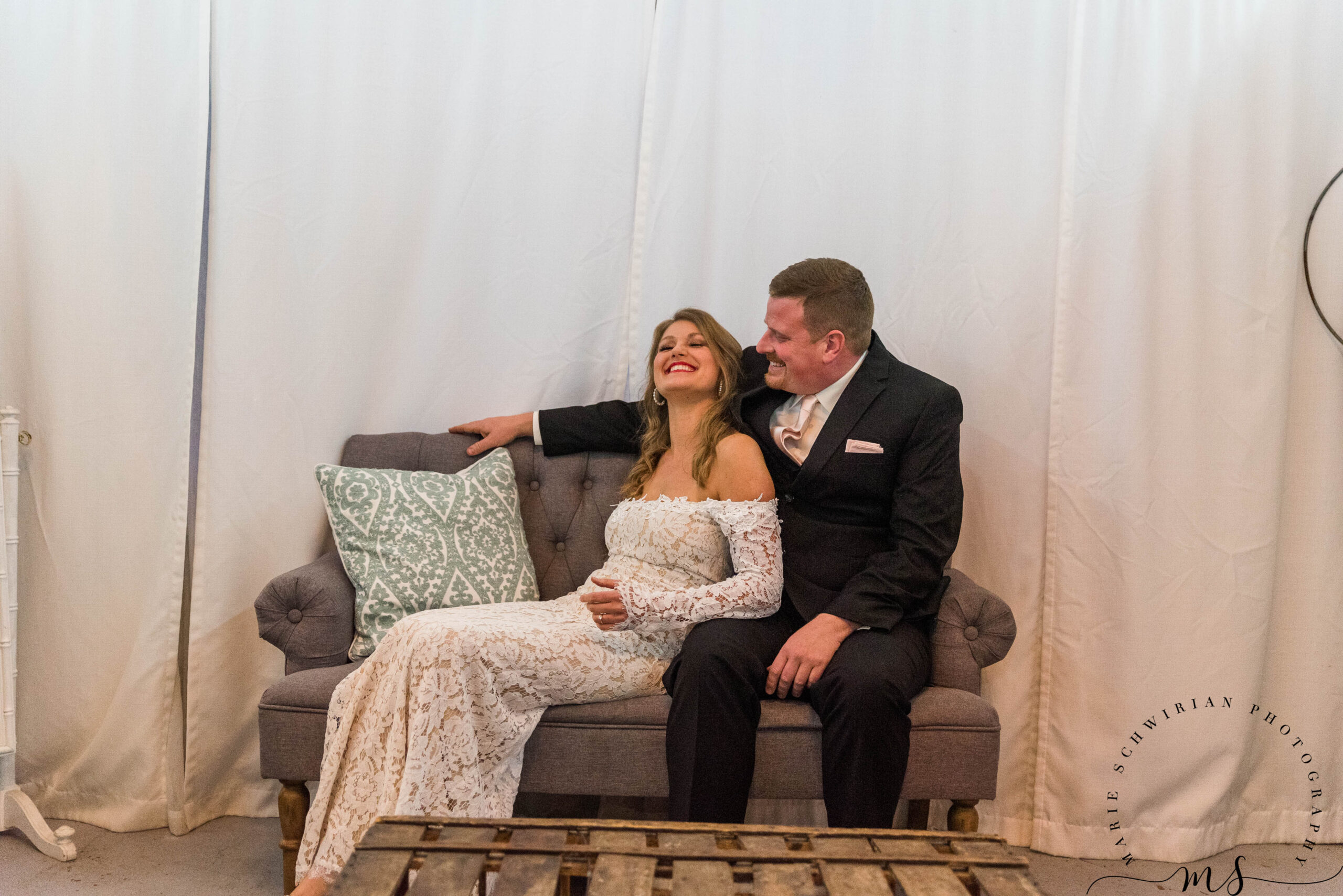 Two people sitting on a couch on their wedding day at the Barn at Dunvilla