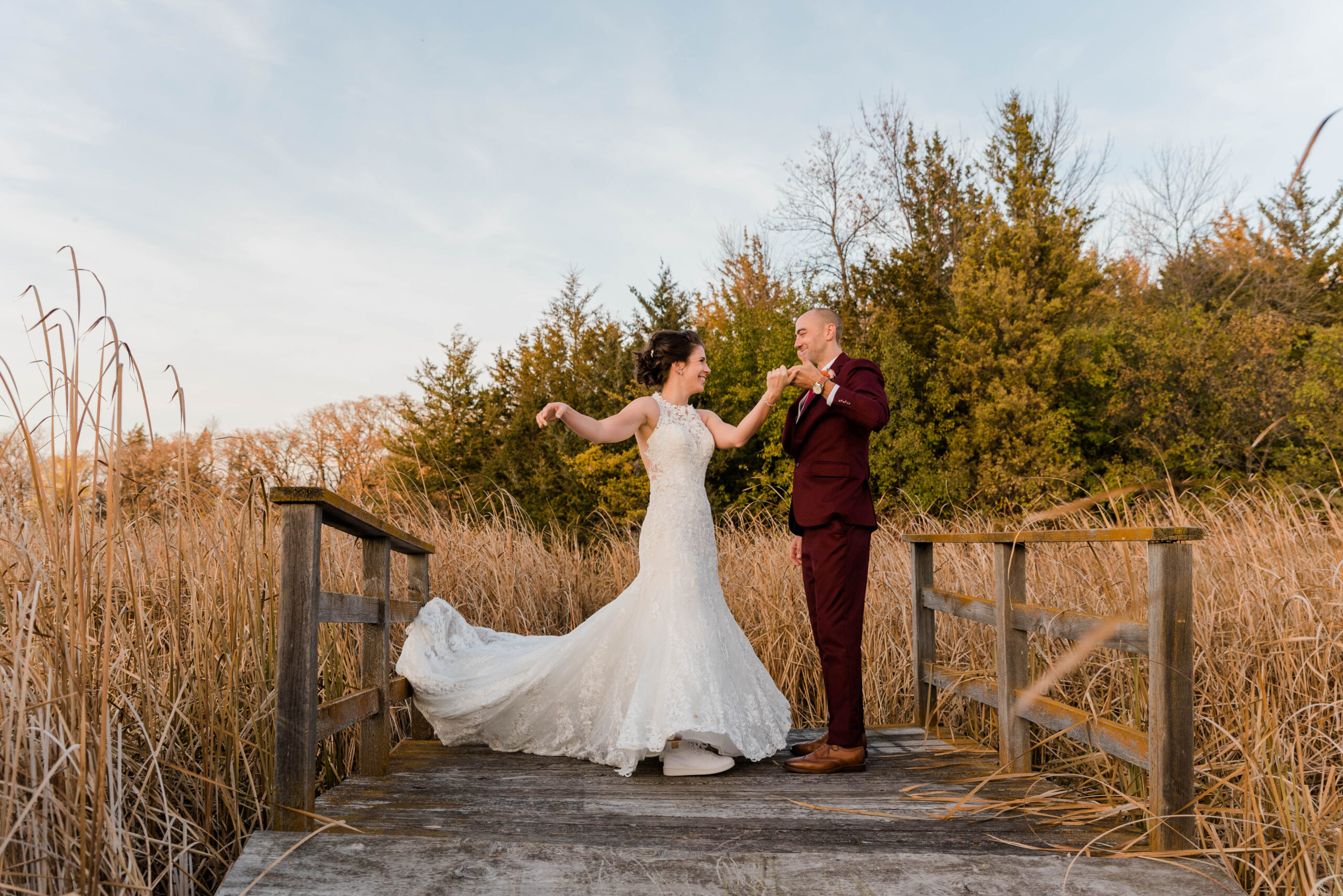 Wedding Photo of two people; Groom wearing Maroon tux and bride twirling in her white gown.