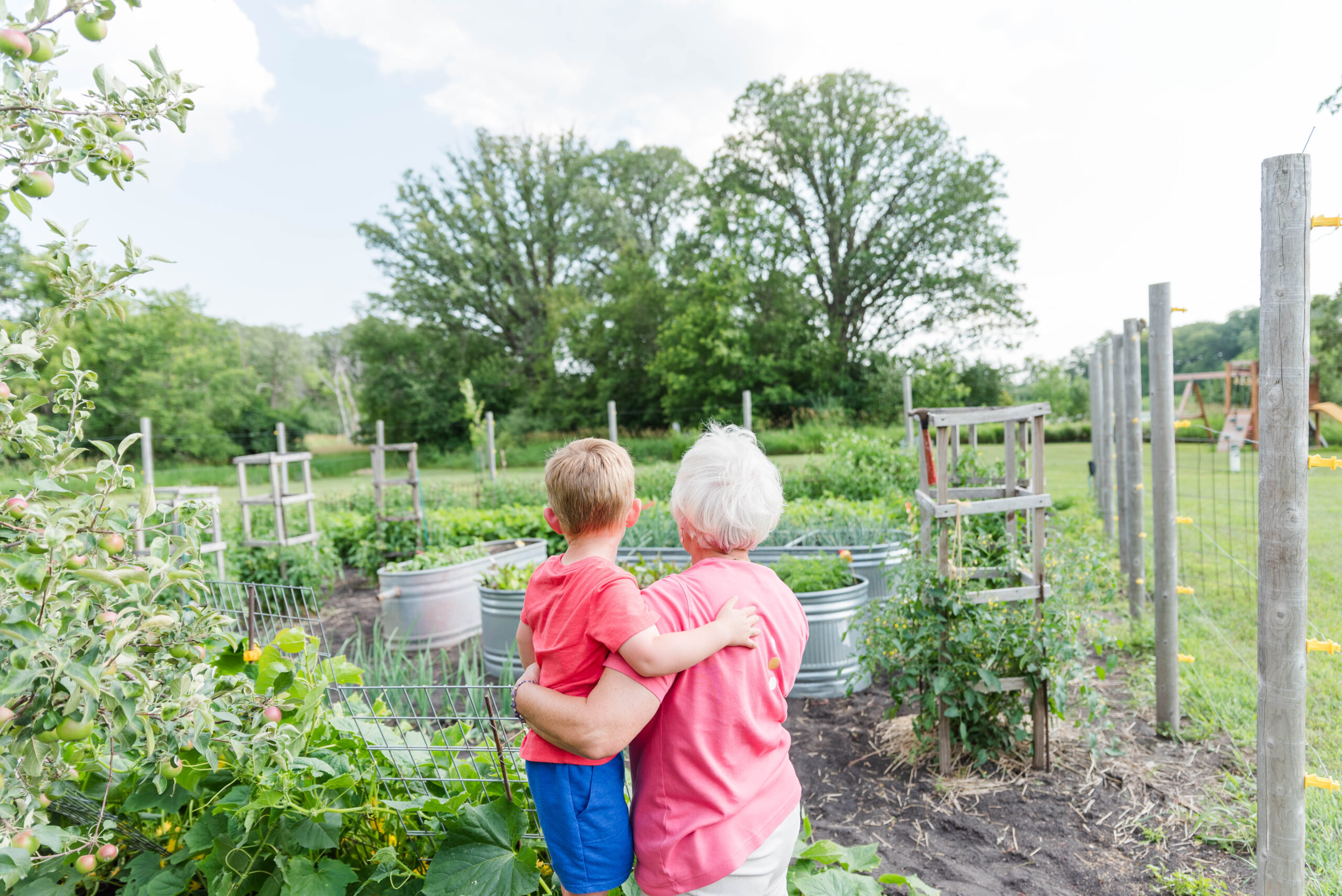 Little Boy and his grandma with their arms wrapped around each other looking at the garden