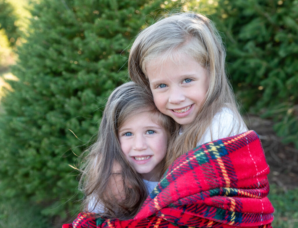 Two Little Girls wrapped in a red plaid blanket