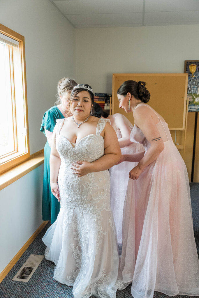 Bride and bridesmaids getting the bride ready in her wedding dress. 