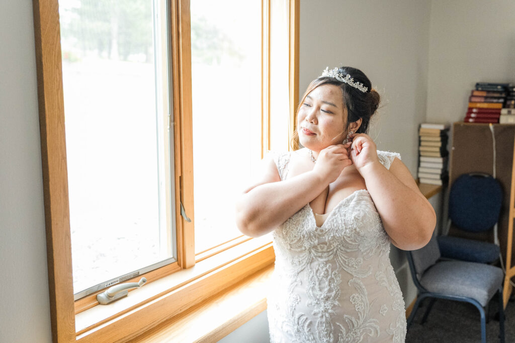 Bride getting ready in front of a window before her wedding day. 