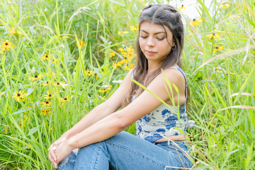 Senior Session in Pelican Rapids MN; in a field of yellow flowers, wearing a blue top and jeans. 